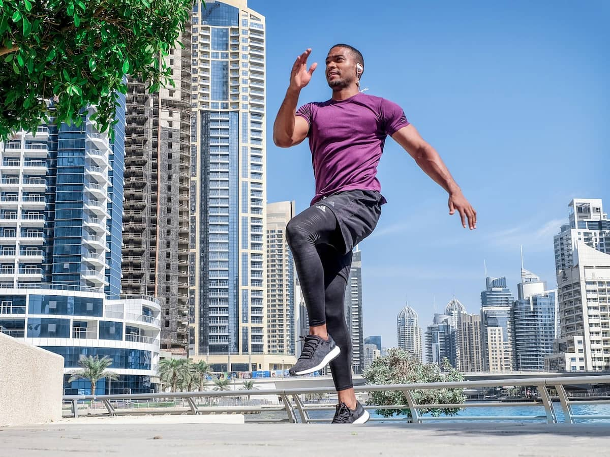 A man performing running drills in front of a city scape